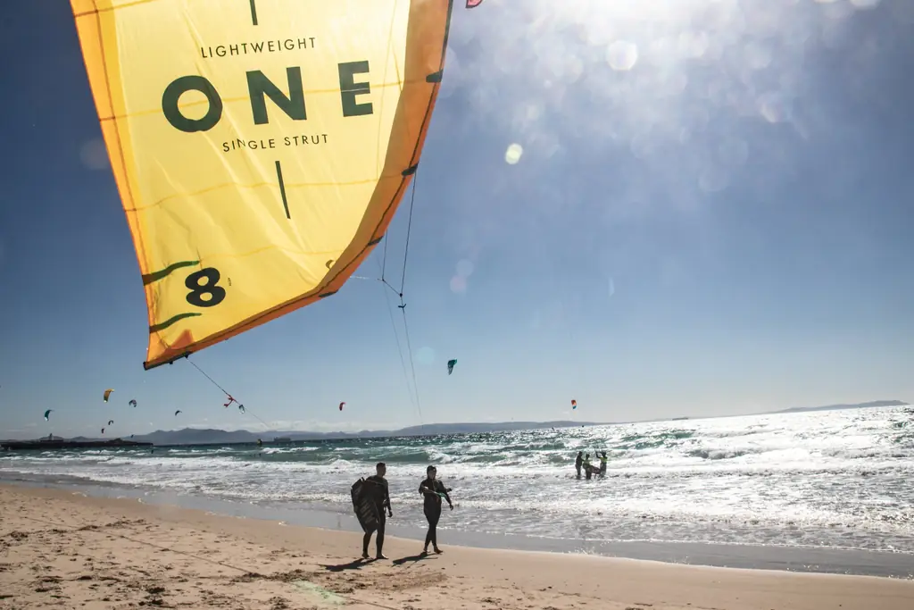 Gelber Airush-Kite am Strand von Los Lances, im Hintergrund Kiteschüler