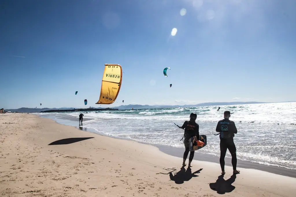Monitor y alumna con tabla en la playa de Los Lances, con una cometa amarilla Airush