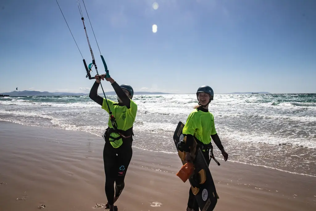 Dos alumnas de kite con barra y tabla en la playa de Los Lances